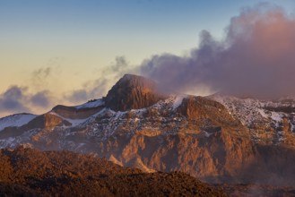 Rugged mountain landscape in the light of the setting sun, surrounded by clouds, UNESCO World