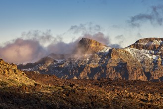 Steep mountains in the evening light with fog and clouds that create a mystical atmosphere, UNESCO