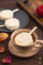 ?hocolate Ice cream in white glaze, cup of coffee, on brown wooden background, side view, close up,