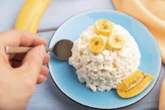 White ?ottage cheese, Curd, with Banana with hand on blue wooden background and orange textile,