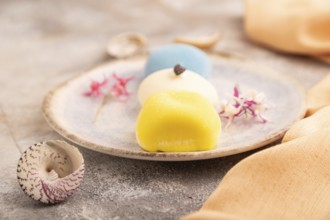 Japanese Mochi Cakes on brown concrete background and orange textile, side view, close up,
