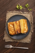 Fried crispy pancakes with meat and cheese on brown wooden background and linen textile. top view,