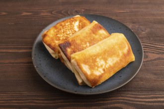 Fried crispy pancakes with meat and cheese on brown wooden background. side view, close up