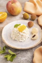 White ?ottage cheese, Curd, with orange and lychee on brown concrete background and orange textile,