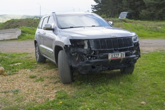 Damaged dark jeep standing on a roadside meadow, Georgia