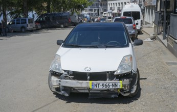White car with damaged front in an urban environment, Georgia