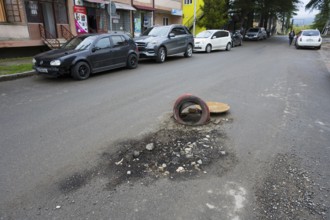 Street scene with cars along the sidewalk and a tire marking a pothole, Martvili, Mingrelia-Upper