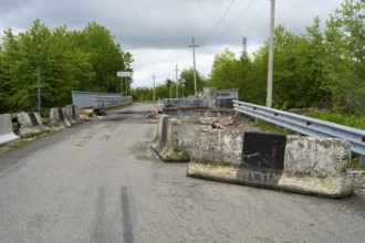 Road with concrete barriers and bridge in a rural area under cloudy sky, bridge over the Techuri