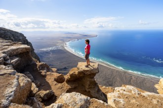 Woman enjoying the view from the Risco de Famara cliffs on Famara beach, Playa de Famara with La