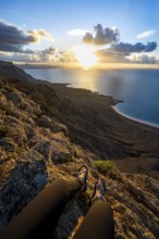 First person view, legs of a woman sitting on a steep cliff, view of sea and coast, Mirador del