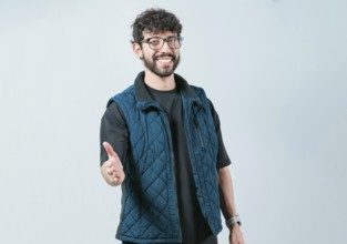Friendly handsome guy greets you with open hand isolated. Male person extending her hand to the