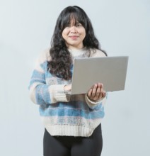 Beautiful asian girl using laptop and looking at camera isolated. Smiling asian woman using