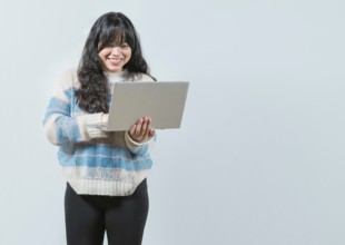 Smiling asian girl holding and looking on laptop screen isolated. Portrait of beautiful asian woman
