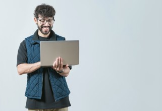 Handsome young man with glasses holding and looking on laptop screen. Portrait of Bearded guy using