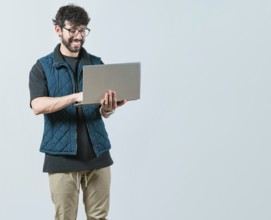 Portrait of Bearded guy using and looking laptop isolated. Handsome young man with glasses holding