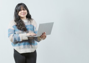 Smiling asian woman using notebook and looking at camera with copy space. Beautiful asian girl