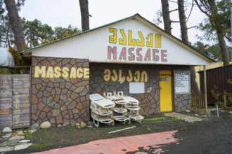 Colourful building with massage signs and stacked loungers outside, beach massage equipment with