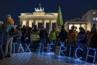 Participants set up glowing letters with the inscription Tax The Rich at the international climate