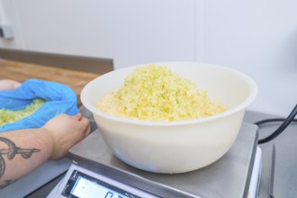 Person holding bags while bowl of sugar is on the scale in a kitchen, Christmas baking,