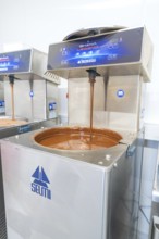 Chocolate flows from a machine into a metallic container, Weihnachtsbacken, Haselstaller Hof,