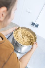 A person holds a large mixing bowl with dough in a kitchen, Christmas baking, Haselstaller Hof,