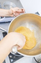 A person is stirring a yellow dough in a pan on a stove, Christmas baking, Haselstaller Hof,