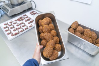 Various rectangular metal containers full of brown chocolate chocolates in a kitchen, Christmas