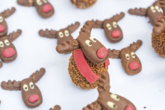 Reindeer chocolate chip cookies with red noses and white eyes, presented on a white background,
