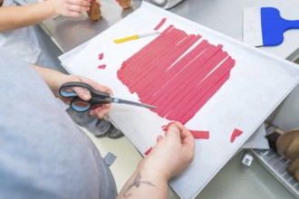 Red strips are cut with scissors on a baking sheet, Weihnachtsbacken, Haselstaller Hof, Wildberg,
