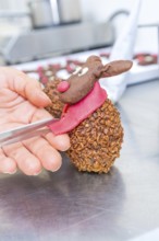 Hand sculpting a chocolate reindeer praline with red scarf and nose, Christmas baking, Haselstaller