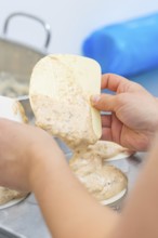 Dough is held by one hand with a silicone spatula and poured into a mold, Weihnachtsbacken,