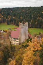 A medieval castle with red tiled roofs surrounded by thick forests in autumn, Berneck Castle,