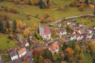 A historic castle towers over an autumnal village in extensive meadows, Berneck Castle,