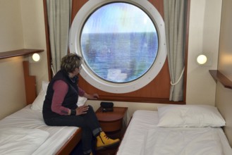 Woman looking out of her ship cabin at the sea, Baltic Sea, Color Line ferry, Schleswig-Holstein,