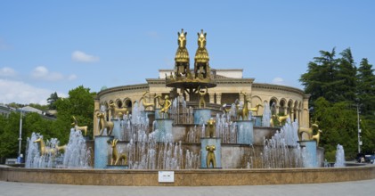 Large fountain with golden statues in an architectural and green setting, Colchis Fountain, David