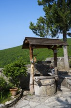 Rustic fountain with wooden roof surrounded by nature and plants in sunny weather, Motsameta