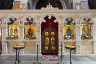 An altar decorated with icons in a church, candles shining in front of it, Motsameta monastery,