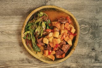 A warm bowl of beef stew features tender chunks of meat, potatoes, carrots, and bell peppers.