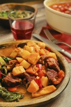 A hearty beef stew with tender chunks of beef meat alongside carrots and bell peppers is served in