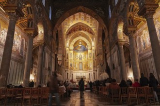 Magnificent sacral interior of a church with mosaics and golden decorations, filled rows of seats,