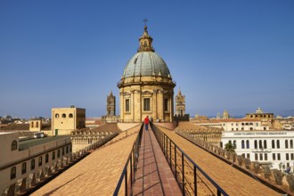 A person walks on a roof in Palermo to the historic dome with clear sky in the background, Palermo,