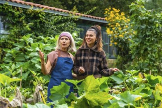 Mother and adult daughter enjoying time together in a lush green garden, the older woman teaching