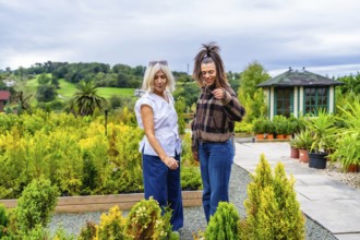 Mother and daughter browsing potted plants and small trees at a garden center, enjoying a relaxed