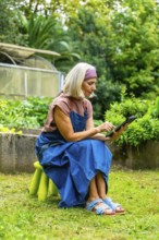 Senior gardener using a tablet to monitor and manage a smart home garden, planning tasks and