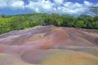 Bright red hills against thick tropical greenery under a clear sky in Mauritius. Africa, East