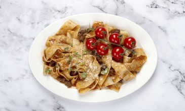 Pappardelle pasta with bolognese sauce, topped with parmesan cheese and cherry branch, homemade, no