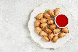 Fried mini chebureks, with sauce, on a decorative plate, hard light, no people