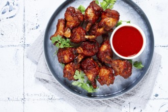 Crispy pieces of fried chicken, on a plate with sauce and herbs, in a modern kitchen environment,