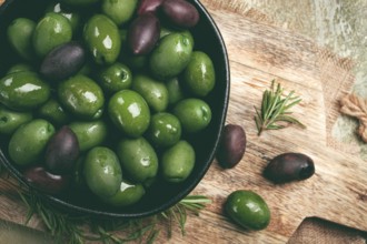 Chalkidiki olives, classic Greek green olives, in a bowl on a cutting board, top view, without