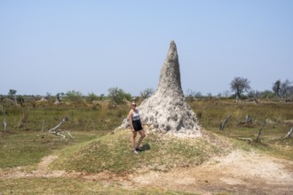 Tourist standing in front of large termite hill, Moremi Game Reserve, Botswana